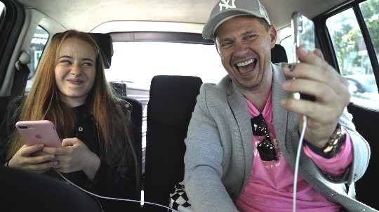 Influencer Leonie in the car together with her father. He makes an exciting phase while Leonie seems not very excited.