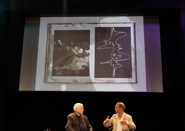 Alexander Kluge und Claudius Seidle auf der Bühne im Hintergrund ein projeziertes Bild